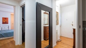 A room with a bed, a dresser, a mirror, and a door leading to another room. - Auditorium Roof Top Apartment (Roma)