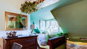 A room with a wooden desk, a chair, a sofa, a mirror, and a window with a view. - Auditorium Roof Top Apartment (Roma)