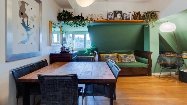 A dining area with a wooden table and chairs, a green sofa, and a hanging plant. - Auditorium Roof Top Apartment (Roma)