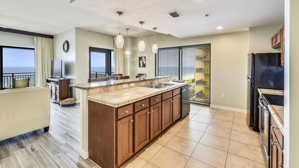 A modern kitchen with a large island, built-in appliances, and a view of the ocean. - Origin at Seahaven 1036/1038 - 2 Bedroom Unit 2 Home by RedAwning (Panama City Beach)