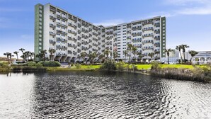 A multi-story hotel with a central courtyard, surrounded by palm trees and a body of water. - Recently Renovated 2bd, Sleeps 6 Pinnacle Port, W/ Boat Ramp 2 Bedroom Condo by RedAwning (Panama City Beach)