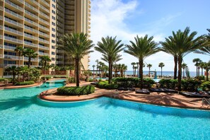 Relax by the infinity pool surrounded by palm trees and lounge areas, with expansive views of the surrounding landscape.