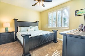 Cozy bedroom with a dark wood bed frame, nightstands, and a ceiling fan for comfortable ventilation.