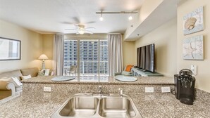 A modern kitchen with granite countertops, a double sink, and a ceiling fan. - Shores of Panama 808- 1 Bedroom+Bunk Room, Free Fun! Updated! Sleeps 6. 1 Condo by RedAwning (Panama City Beach)