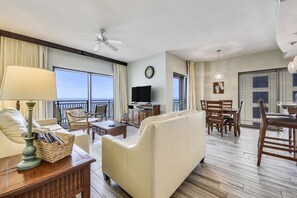 Relax in a spacious living area with a sofa set, dining table, and television, plus a balcony offering ocean views.
