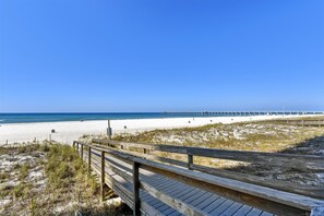 Een strand met een houten boardwalk die naar een pier leidt, die zich in de oceaan uitstrekt.