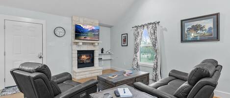 A living room with two leather sofas, a fireplace, a television, and a framed picture on the wall.