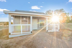 A two-story building with a porch, a sign reading "MALTESE", and a number "151" on the front. - Appian Way Maltese Cottage 1 Bedroom Cabin by RedAwning (Fredericksburg)