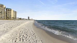 A beach with a sandy shore, a clear sky, and a high-rise building in the background. - Laketown Wharf 1003, Gulf View, Sleeps 6. Free Fun! Updated! 1 Bedroom Condo by RedAwning (Panama City Beach)