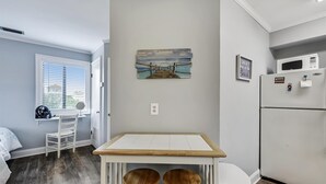 Une cuisine compacte avec un réfrigérateur blanc, un four à micro-ondes et une petite table à manger accompagnée de deux tabourets.