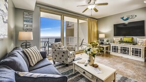 A living room with a sofa, armchairs, a coffee table, a TV, and a balcony with a view. - Shores of Panama 1704 - 2 Bedroom + Bunk Room . Updated! Res. Parking 2 Condo by RedAwning (Panama City Beach)