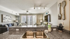 A modern kitchen with a granite countertop, double sink, and a view of high-rise buildings through the window. - Shores of Panama 1704 - 2 Bedroom + Bunk Room . Updated! Res. Parking 2 Condo by RedAwning (Panama City Beach)