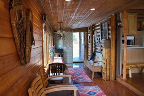 A wooden cabin interior with a dining area, kitchen, and a large window. - Cozy chalet on the Swan River at Tiger Run (Breckenridge)