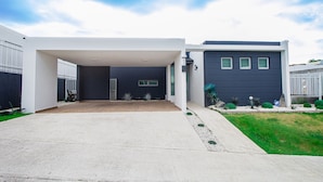 A modern two-story house with a covered driveway and a well-maintained lawn. - House close to the beach, adventure parks and authentic Puerto Rican restaurants (Luquillo)
