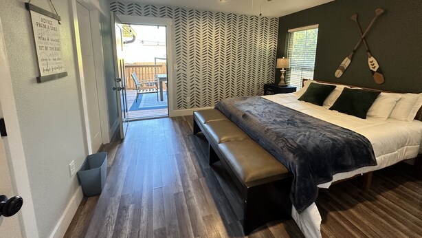 Un dormitorio con cama, banco, ventilador de techo y vistas al exterior.