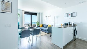 Eine moderne Küche mit Kochinsel, einem Essbereich mit Stühlen, einer Couch und einem großen Fenster mit Aussicht.