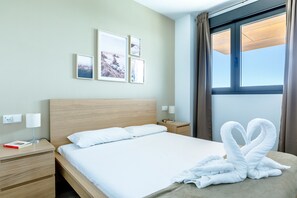 Ein Hotelzimmer mit einem hölzernen Bett, weißer Bettwäsche, einem Nachttisch mit Lampe und gerahmten Bildern an der Wand.