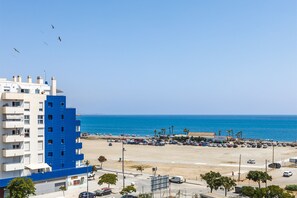 Ein Hotel an der Küste mit blau-weißer Fassade, einem Parkplatz und Blick auf den Strand.