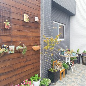 Pared de madera con macetas colgantes y pared de ladrillo con una ventana.