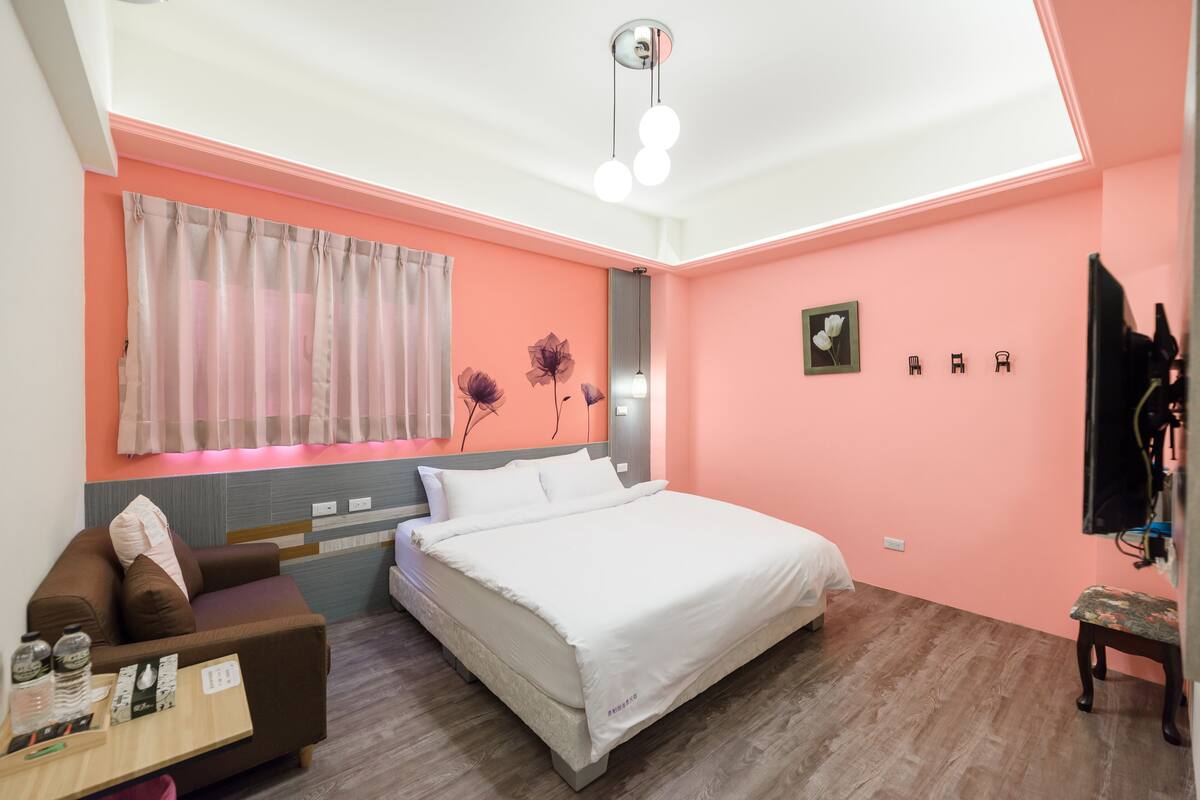 Quarto com cama, sofá, escrivaninha e espelho.