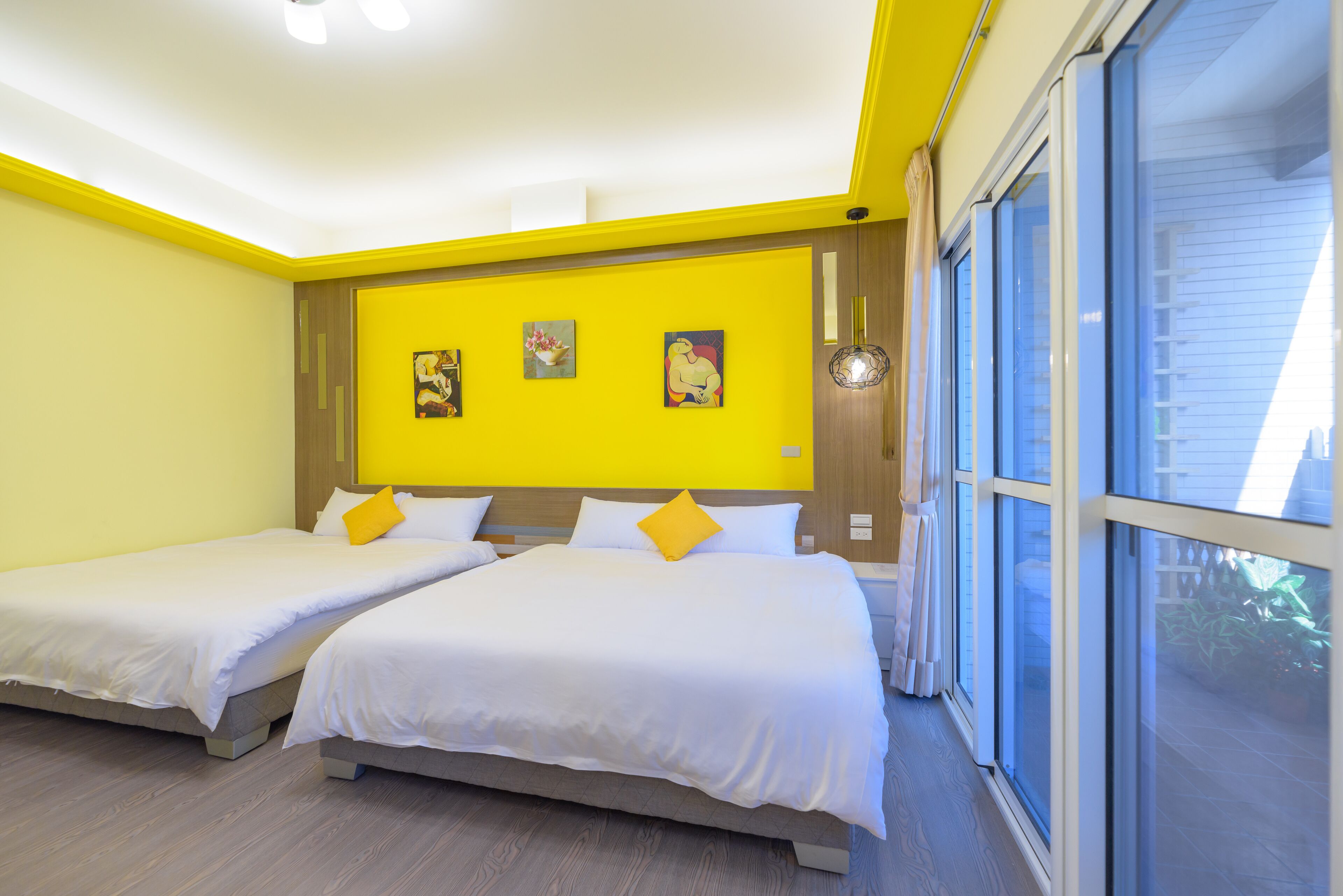 Une chambre d’hôtel avec deux lits, une grande fenêtre et un mur d’accent d’un jaune vif.