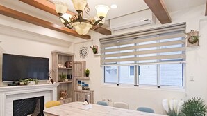 Un espace repas comprenant une table en marbre, des chaises, un lustre, une cheminée et un téléviseur.