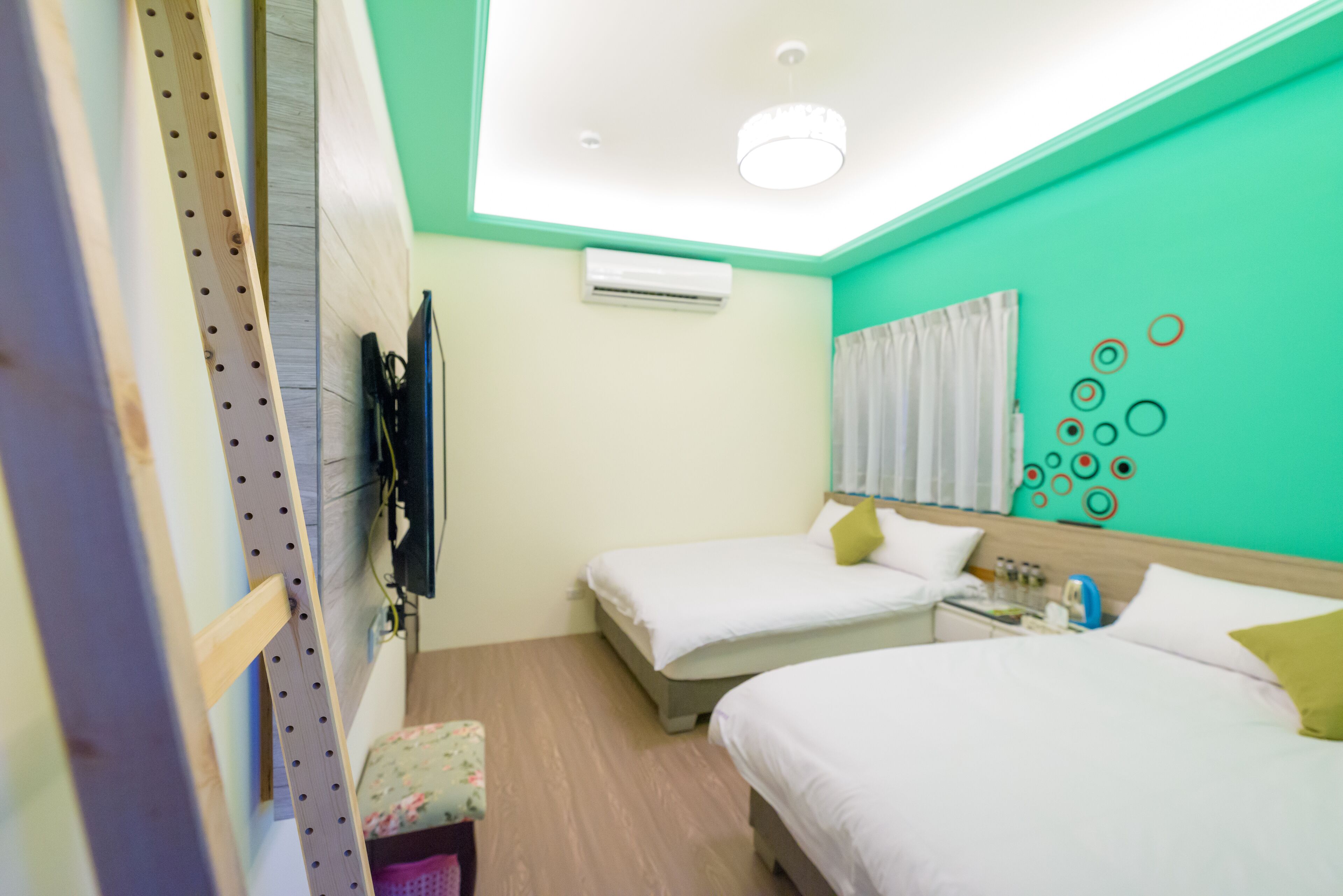 A hotel room with two beds, an air conditioning unit, a television, and a wall with circular decorations.