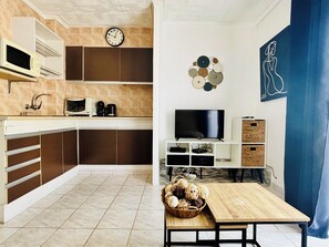 A modern kitchen with a microwave, coffee maker, and a flat-screen TV.