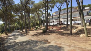 A pathway lined with trees leading to a multi-story building with balconies and outdoor seating. - Mas Vermey nº 6 - Apartment with shared swimming pool - Calella de Palafrugell (Calella de Palafrugell)