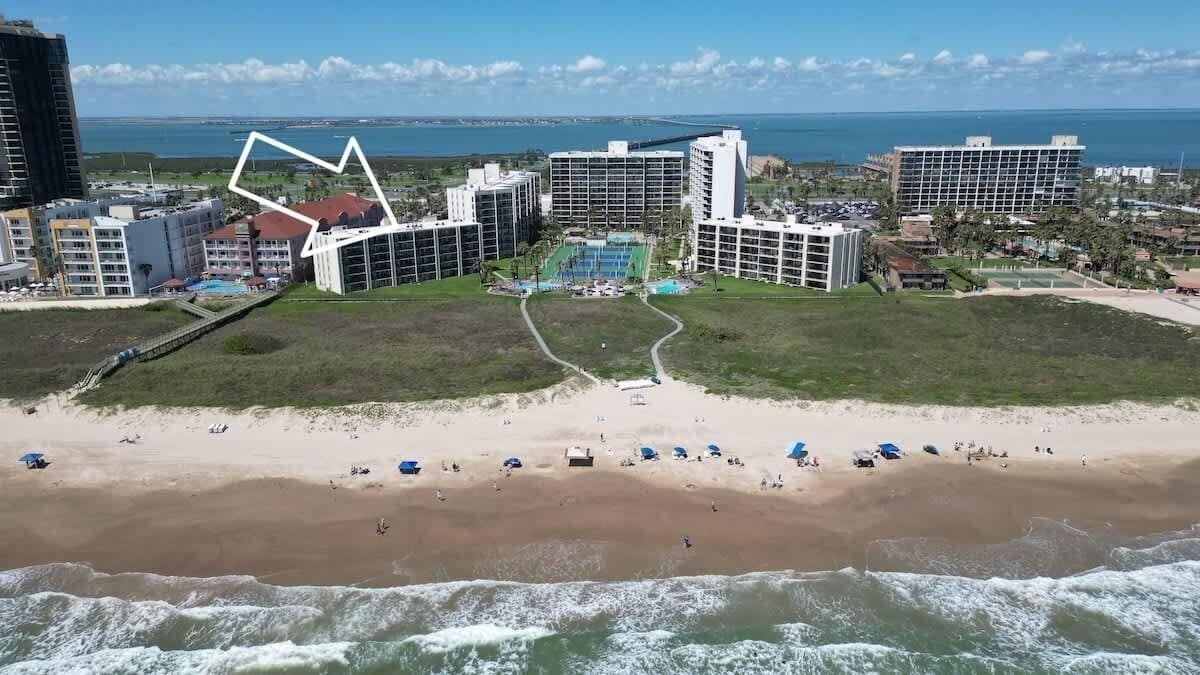 Un hôtel situé sur la côte, composé de plusieurs bâtiments, avec une plage et une vue sur l’océan.