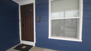 Una casa azul con una puerta marrón y un ventanal grande.