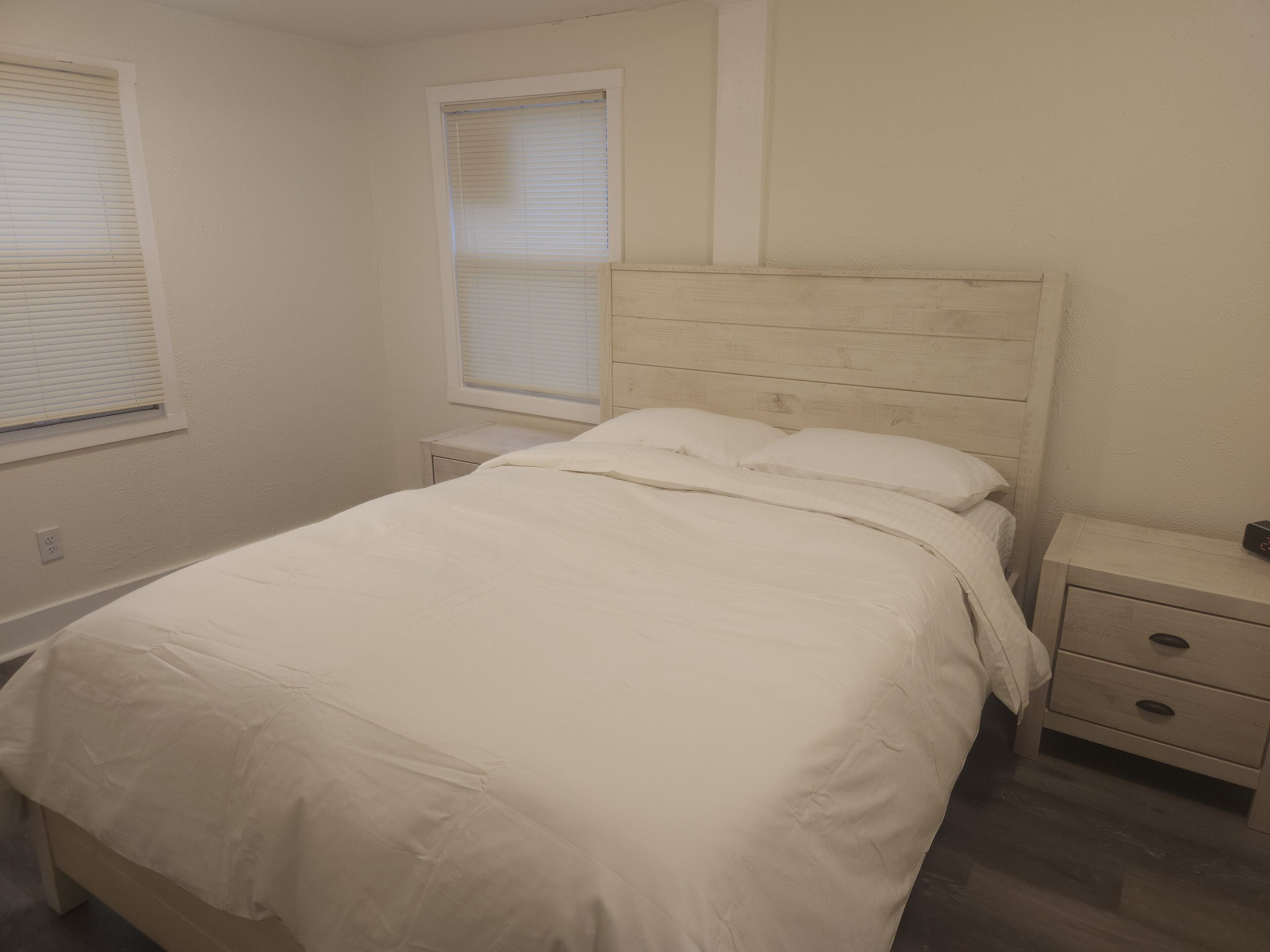 A bedroom with a bed, a nightstand, and a dresser.