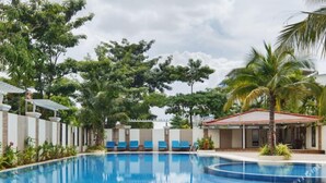 A swimming pool with blue tiles, surrounded by greenery and a covered seating area. - 8008 Hotel (Phnom Penh)