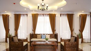 A room with a wooden sofa set, a matching coffee table, and curtains. - 8008 Hotel (Phnom Penh)