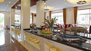 A hotel lobby with a marble reception desk, dining area with red chairs, and large windows allowing natural light. - 8008 Hotel (Phnom Penh)