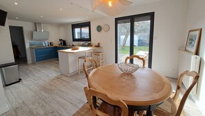 Une cuisine moderne avec un îlot central, une table à manger en bois et des chaises.