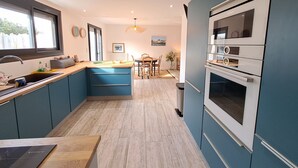 Une cuisine moderne avec des armoires bleues, un plan de travail en bois et un four encastré.