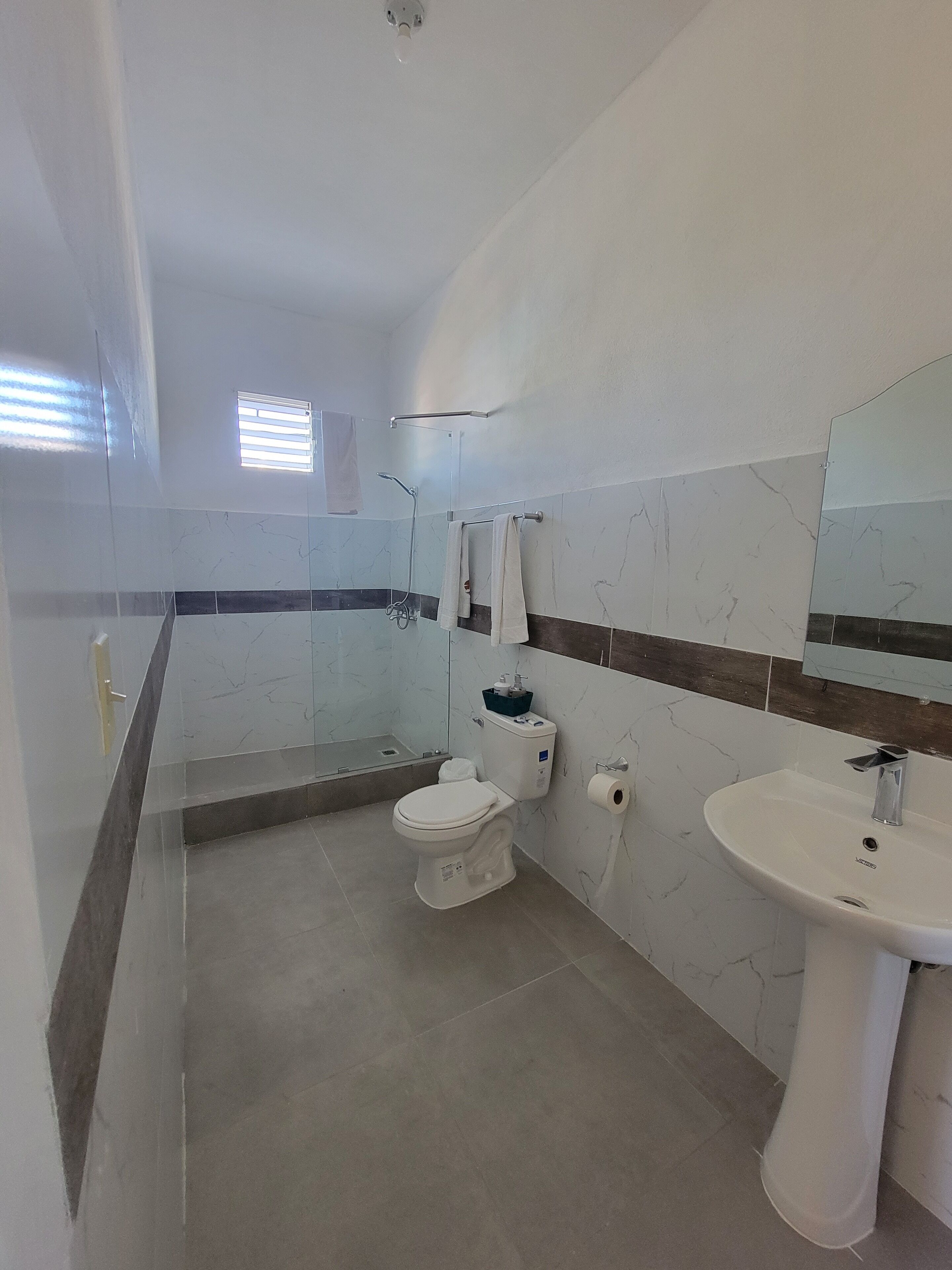 A modern bathroom with a toilet, sink, and shower.