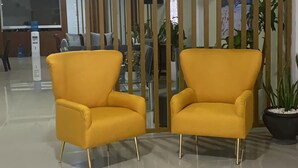 Un espace d’accueil avec deux fauteuils jaunes, une cloison en verre et une plante en pot.