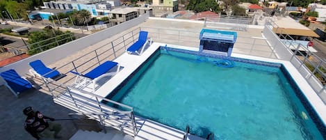 Una piscina al aire libre, sillones reclinables de piscina