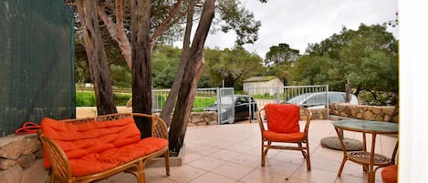 An outdoor patio with wicker furniture and a stone wall.
