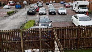 A parking lot with multiple cars and a white camper van.