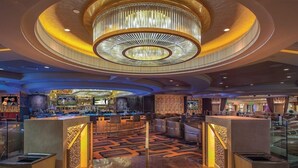 A modern lobby with a central staircase, a bar area, and a patterned carpet. - Suite + Connecting Room at a 4.5⭐️ Hotel (Las Vegas)