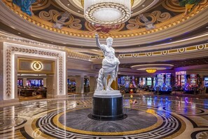 A lobby with a central statue, a chandelier, and slot machines. - Suite + Connecting Room at a 4.5⭐️ Hotel (Las Vegas)