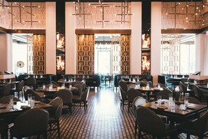 A restaurant with a brick floor, multiple tables and chairs, and a central aisle.