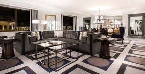Ein modernes Wohnzimmer mit einem Ecksofa, einem Glastisch und einem gemusterten Teppich.