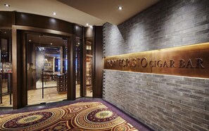 The entrance to Montecristo Cigar Bar with a dark brick wall and a patterned carpet.