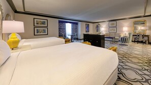 Ein Hotelzimmer mit zwei Betten, einem Schreibtisch, einem Stuhl, einer Lampe und einem gemusterten Teppich.