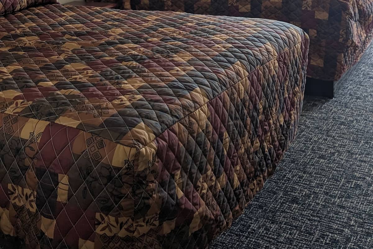 A hotel room with two beds, a framed picture on the wall, and a window with curtains.