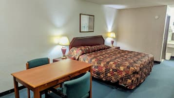 Una habitación de hotel con una cama, una mesa de madera, dos sillas y dos lámparas de noche.